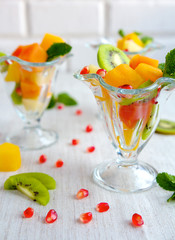 Fruit desserts, salad of pineapple, papaya, pomegranate and mint, kiwi on light background