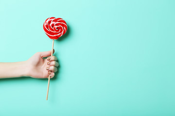 Female hand holding lollipop on green background