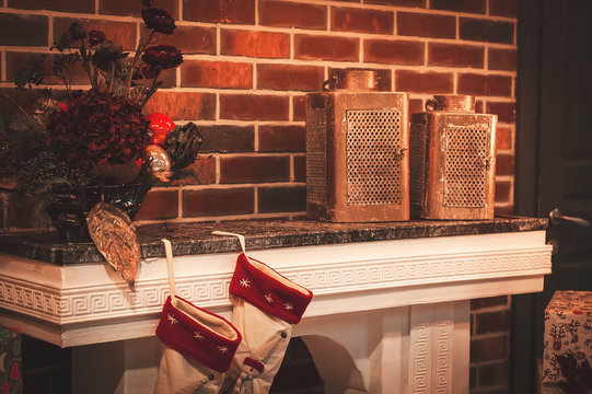 Christmas socks on fireplace, gifts, vintage candles. Christmas room and lighting. 