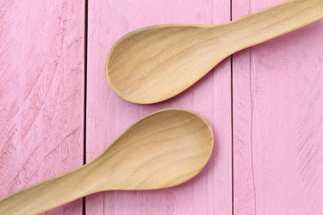 Wooden spoon on pink wood floors.
