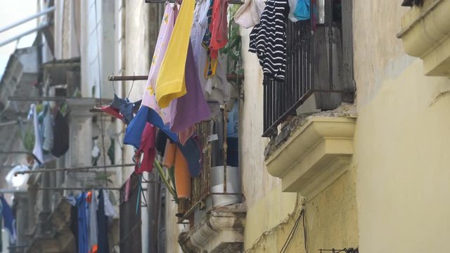 View to old balcony on a colonial Havana street where the multi-colored wet clean washed clothes of local people are drying at summer sunny day