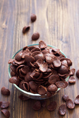 chocolate flakes on bowl on brown background