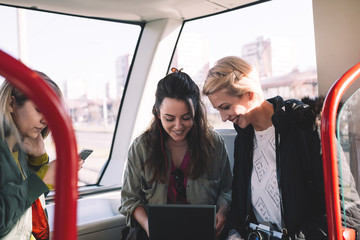 Beautiful young women sitting in tram and doing something on notebook or laptop computer.