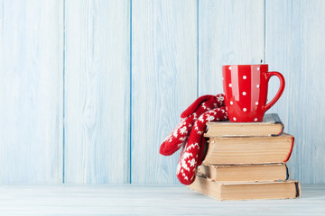 Hot chocolate cup and mittens over books