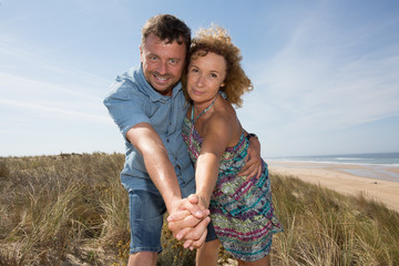 Man and woman couple smiling in sunshine at the beach
