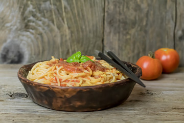 Spaghetti marinara pasta with tomato sauce and basil on rustic h