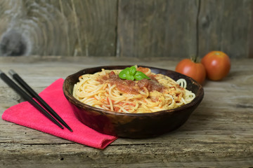 Spaghetti marinara pasta with tomato sauce and basil on rustic h