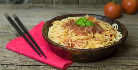 Spaghetti marinara pasta with tomato sauce and basil on rustic h