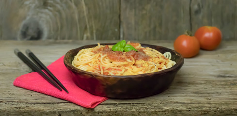 Spaghetti marinara pasta with tomato sauce and basil on rustic h