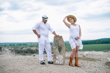 Pregnant woman and man sitting on rock