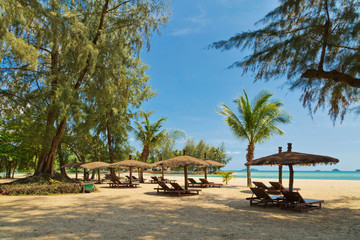 Wooden chairs and umbrellas on white sand beach