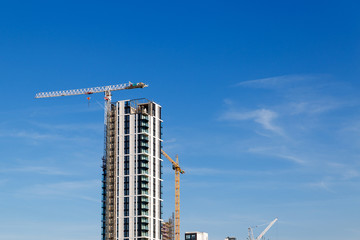 Building crane and construction site under blue sky.