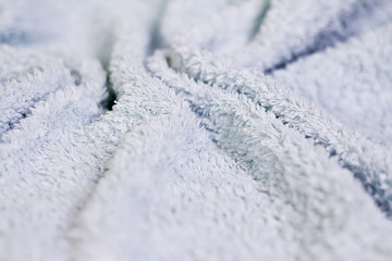 Closeup view of blue towel. Fluffy white background