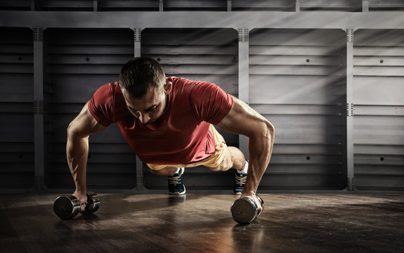 Sport background. Handsome man doing push ups exercise with one hand in fitness gym