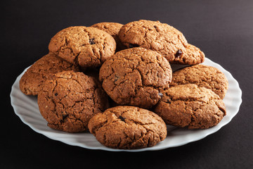 White plate of freshly baked oatmeal cookies with chocolate