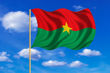 Flag of Burkina Faso waving on blue sky background