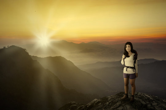Female hiker on a mountain with sunset