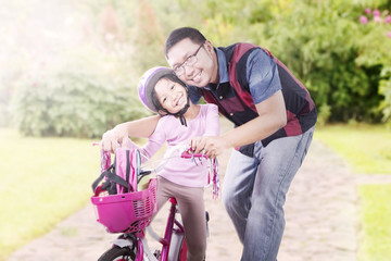 Little child riding bike with her father