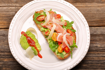 Avocado sandwich on fresh bread with arugula ham tomato and chee
