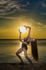Ballerina on lake shore at sunset 
