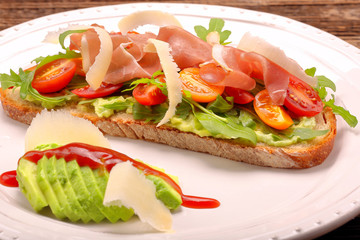 Avocado sandwich on fresh bread with arugula ham tomato and chee