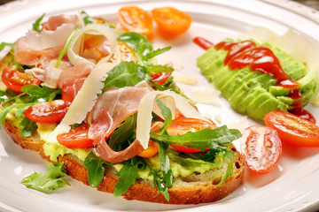 Avocado sandwich on fresh bread with arugula ham tomato and chee