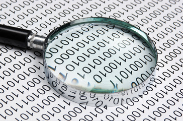 magnifying glass on a binary code