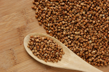 buckwheat groats and wooden spoon on the kitchen table