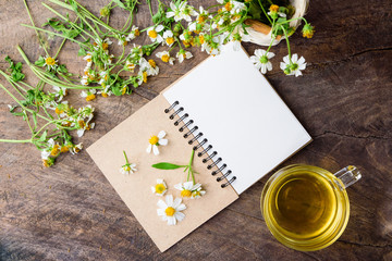 Blank notebook white flower and bas ket of flower and cup of tea on vintage wooden table View from above with copy space