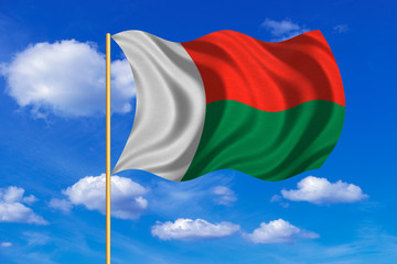 Flag of Madagascar waving on blue sky background