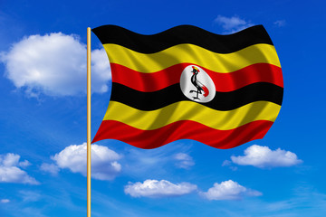 Flag of Uganda waving on blue sky background
