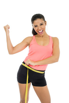 beautiful latin woman in fitness clothes measuring body waist size holding measure tape smiling happy