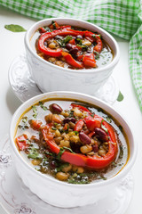 Spiced vegan kidney bean and lentil thick soup with tomatoes and bell pepper. Vintage ceramic bowl on white table.