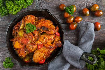 Chakhokhbili, chicken stew, cooked with tomatoes, bell peppers, spices and herbs. Dark wooden background, top view.