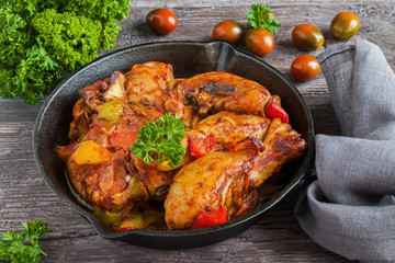 Chakhokhbili, chicken stew, cooked with tomatoes, bell peppers, spices and herbs. Dark wooden background.