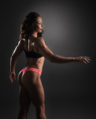Fototapeta na wymiar Back view of female bodybuilder posing in studio