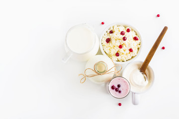 Dairy produce. Milk in bottle, cottage cheese in bowl, kefir in jar, cranberry yogurt in glass, butter and fresh berries. White table, top view.