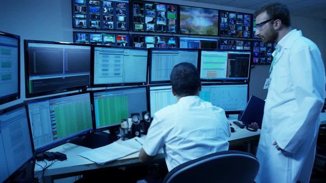 IT Engineers Are Working On Computers and Discussing About Something. Monitoring Room. 