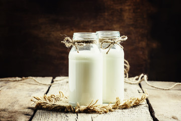 Fresh cow milk or cream in glass bottles, rustic style, vintage