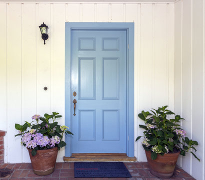 A front entrance of a home with a blue door, Blue front door with flower pots