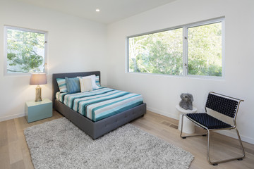 Modern bedroom with fluffy rug, blue bed cover and wooden floor.