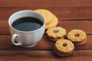 cup of hot coffee and cookies on wooden table background