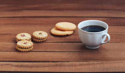 Coffee cup and biscuits on brown wooden table.