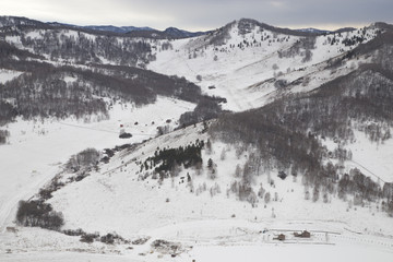 Farm at the foot of the mountains. High mountains loom over the