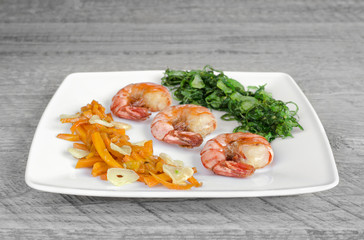 Dish with fried shrimp and vegetables, wooden background. Selective focus.