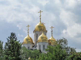 Fototapeta na wymiar Church of all saints at Mamayev Kurgan in Volgograd, Russia. Summer Sunny day, clouds, trees. The Golden domes