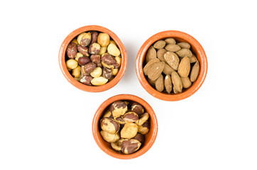 bowls of peanuts hazelnuts and almonds isolated on a white backg