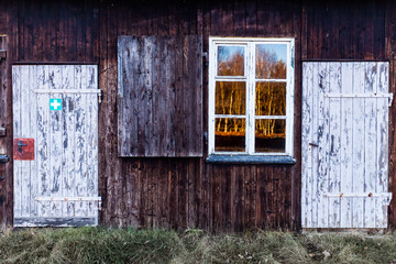 Obraz na płótnie Canvas Wooden house facade with window to sunny forest