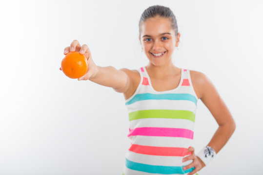 Teen girl for a healthy lifestyle, vitamins winter. active lifestyle schoolchildren. Girl in a bright striped shirt holding an orange in her hand, selective focus