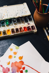 Crop from above view of watercolor palette and paintbrushes.